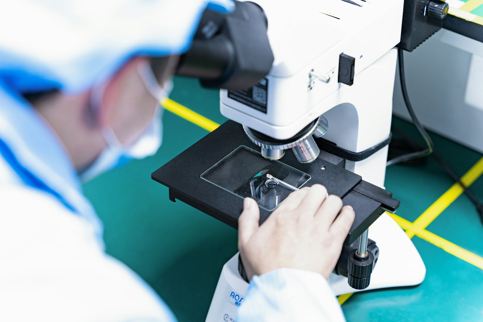 An operator inspecting a board under a microscope